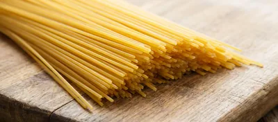 Uncooked dry spaghetti pasta on wooden board